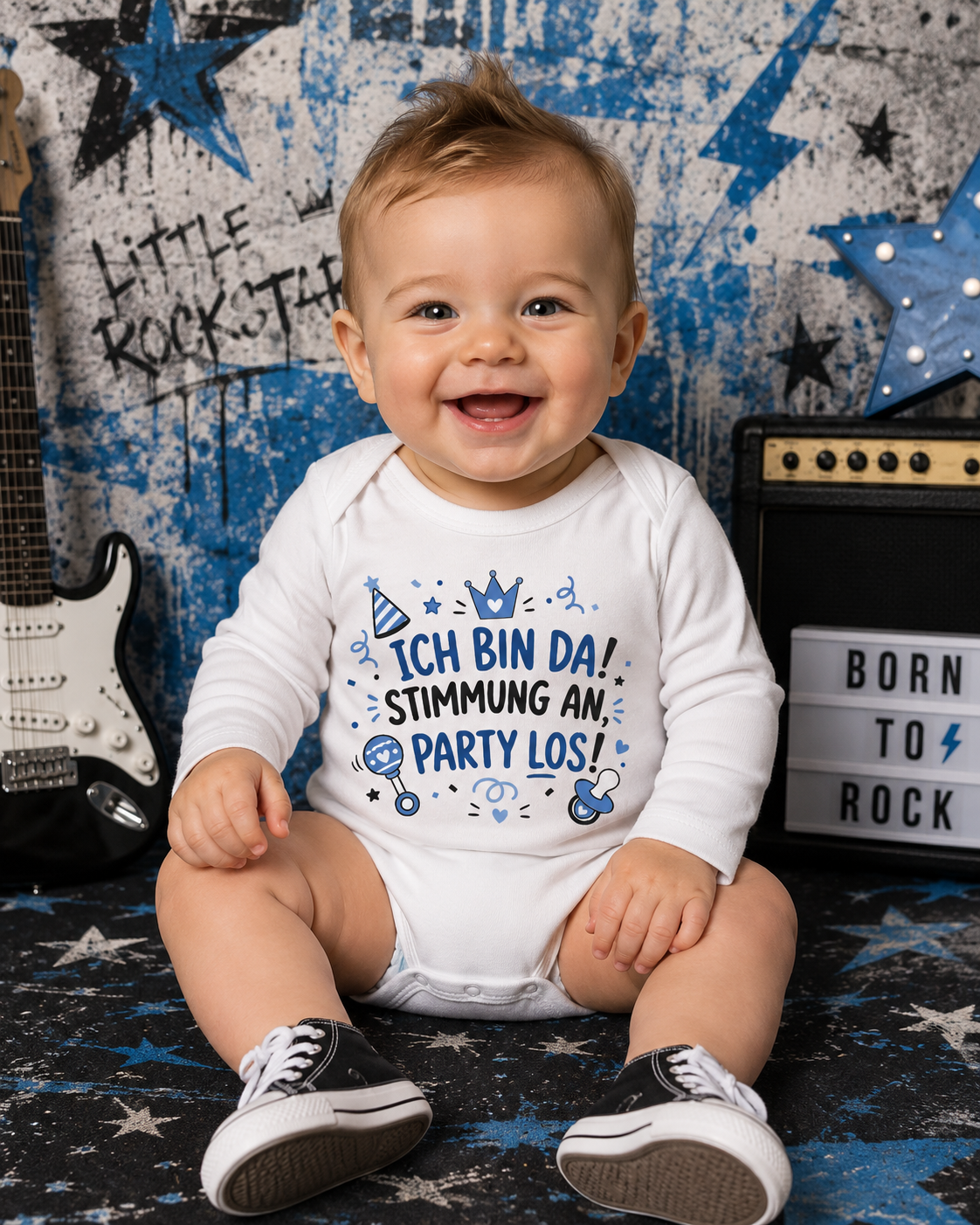 Lachender Baby Junge trägt weißen Langarm-Babybody mit blau-schwarzem Party-Spruchmotiv vor rockigem Hintergrund.