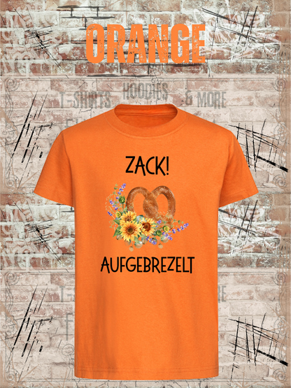 Kinder-T-Shirt „Zack! Aufgebrezelt“ in Orange.