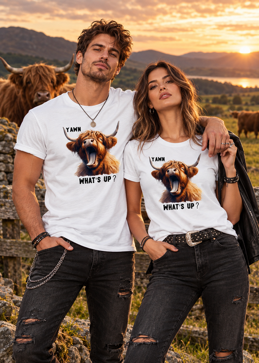 Rockiges Paar trägt weiße Highland Kuh T-Shirts mit lustigem Yawn What's Up Motiv auf einer Hochlandrinder-Weide bei Sonnenuntergang